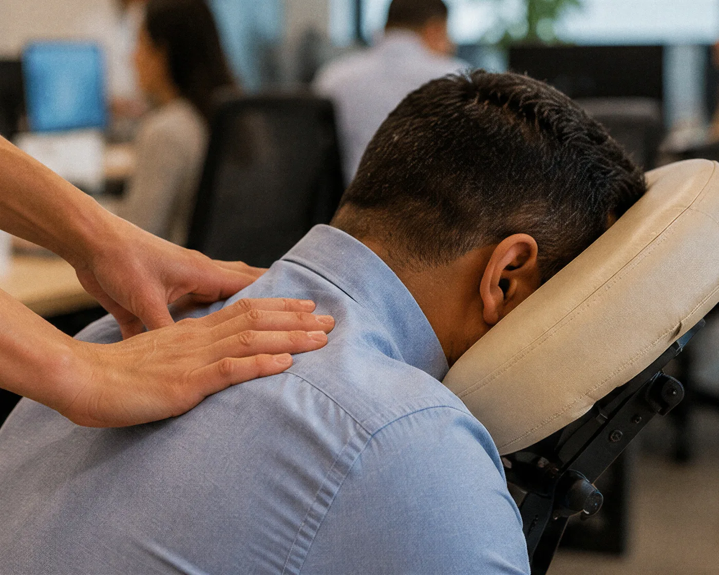 Quick massage num escritório aberto, colaborador atendido na cadeira enquanto a equipe segue trabalhando ao fundo