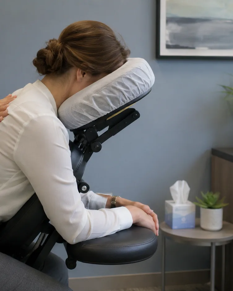 Quick massage em sala comercial, colaboradora sentada e vestida na cadeira ergonômica