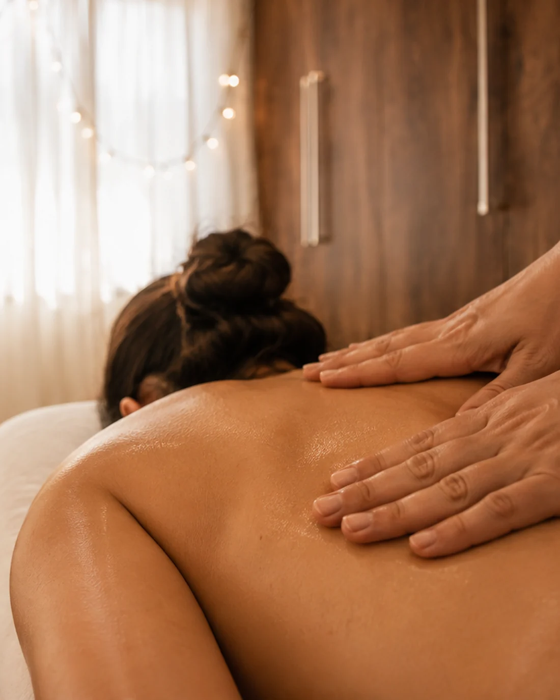 Mãos deslizando com óleo sobre as costas durante uma massagem relaxante, na sala da Essência do Cuidar
